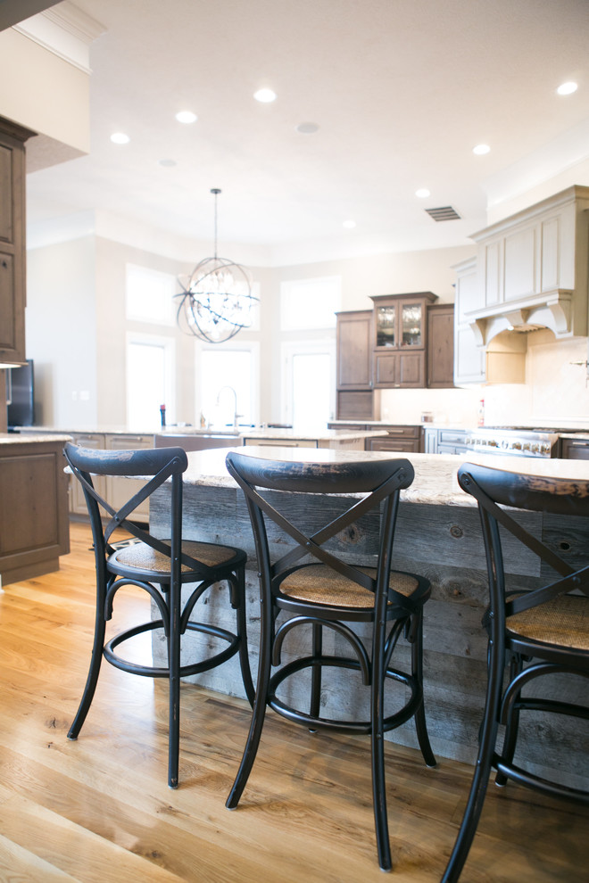 Inspiration for a large transitional u-shaped medium tone wood floor and brown floor kitchen remodel in Indianapolis with a farmhouse sink, raised-panel cabinets, dark wood cabinets, granite countertops, white backsplash, subway tile backsplash, paneled appliances, an island and multicolored countertops