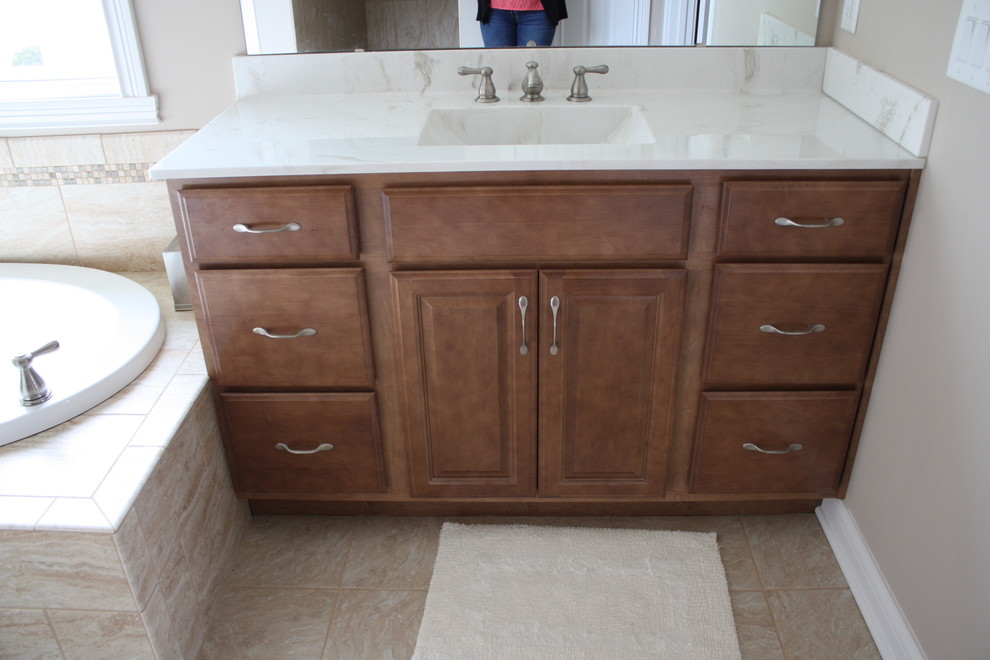 Design ideas for a small transitional master bathroom in Indianapolis with raised-panel cabinets, medium wood cabinets, marble benchtops and a drop-in tub.