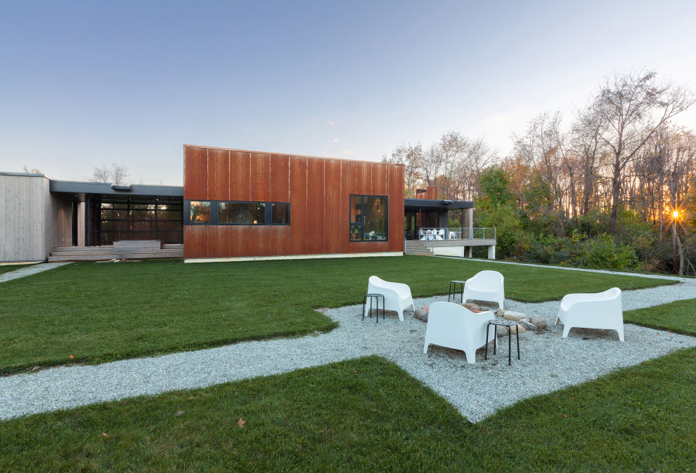 Идея дизайна: маленький, одноэтажный, оранжевый частный загородный дом в стиле модернизм с облицовкой из металла, односкатной крышей и металлической крышей для на участке и в саду