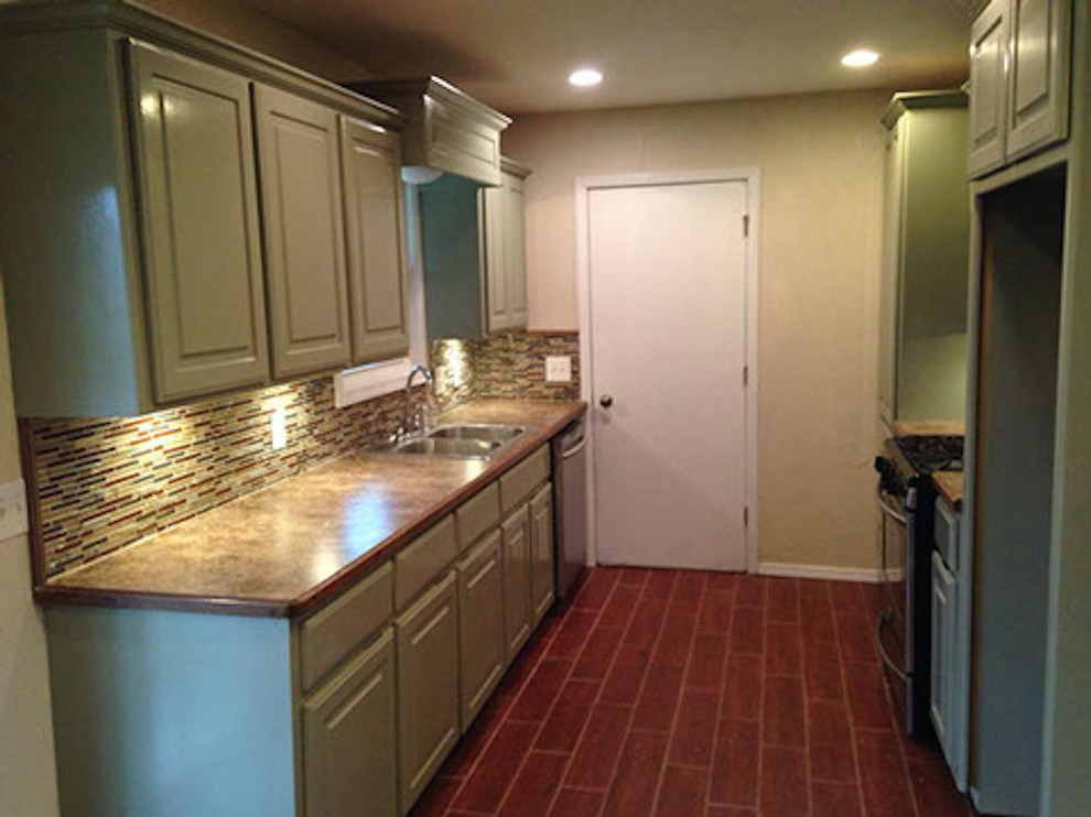 Example of a small transitional galley laminate floor eat-in kitchen design with a double-bowl sink, raised-panel cabinets, green cabinets, multicolored backsplash, matchstick tile backsplash, stainless steel appliances and no island