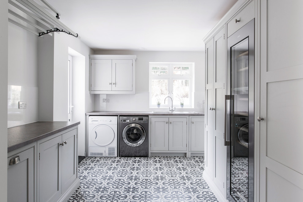 Design ideas for an expansive contemporary u-shaped utility room in Kent with a single-bowl sink, shaker cabinets, grey cabinets, laminate benchtops, grey walls, ceramic floors, a side-by-side washer and dryer, yellow floor and grey benchtop.