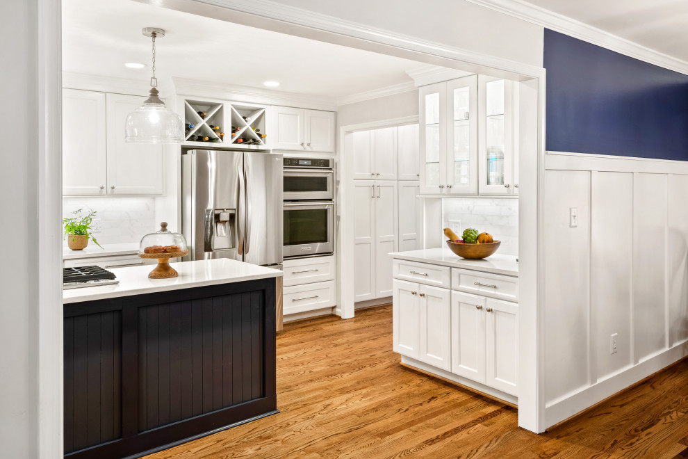 Inspiration for a mid-sized beach style l-shaped eat-in kitchen in Raleigh with shaker cabinets, white cabinets, quartz benchtops, white splashback, marble splashback, stainless steel appliances, medium hardwood floors, with island, brown floor and white benchtop.