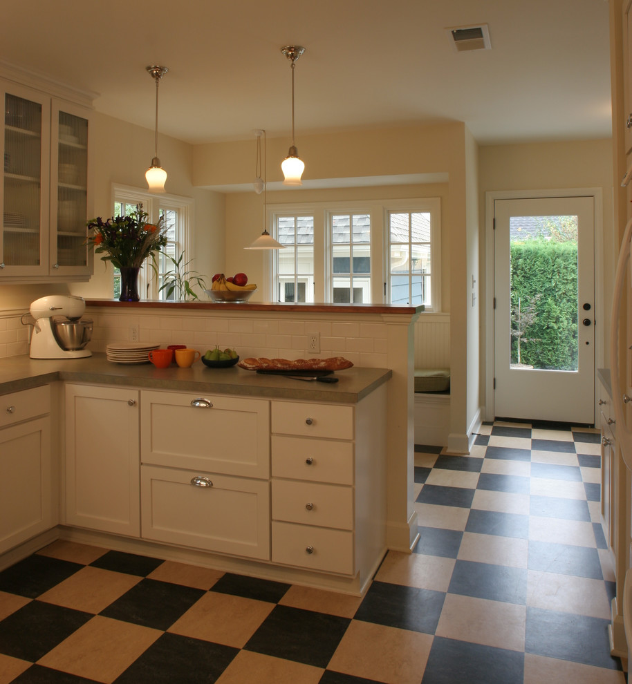 Photo of an arts and crafts u-shaped separate kitchen in Portland with recessed-panel cabinets, white cabinets, laminate benchtops, white splashback, subway tile splashback and linoleum floors.