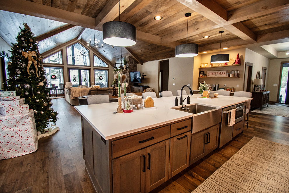 Example of a large mountain style single-wall medium tone wood floor, multicolored floor and coffered ceiling open concept kitchen design with a farmhouse sink, flat-panel cabinets, medium tone wood cabinets, quartzite countertops, stainless steel appliances, an island and multicolored countertops