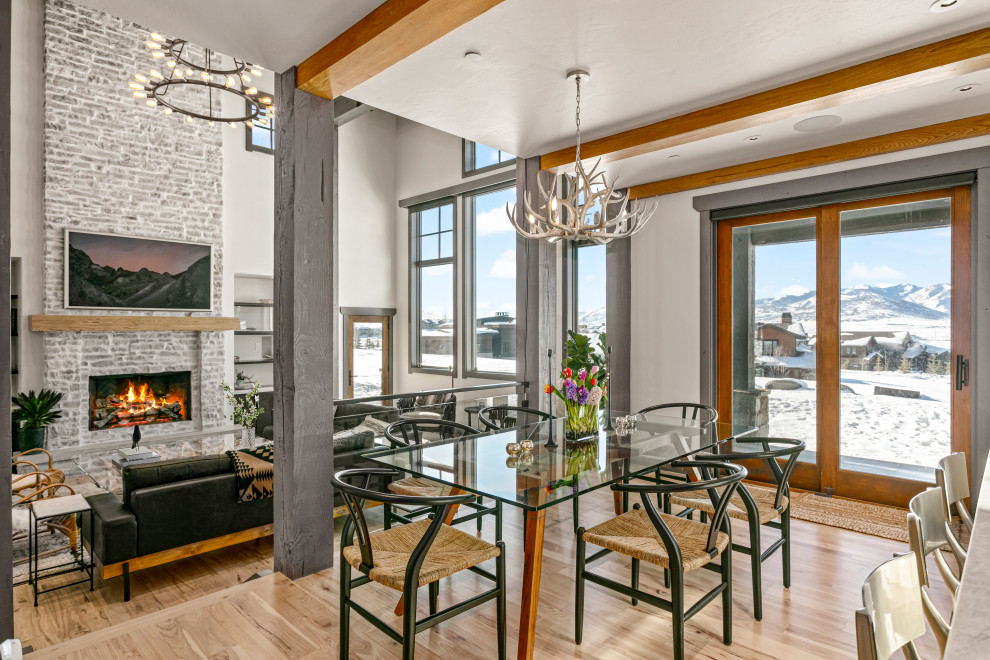 Example of a large minimalist light wood floor, brown floor and exposed beam breakfast nook design in Salt Lake City with white walls, a standard fireplace and a stone fireplace