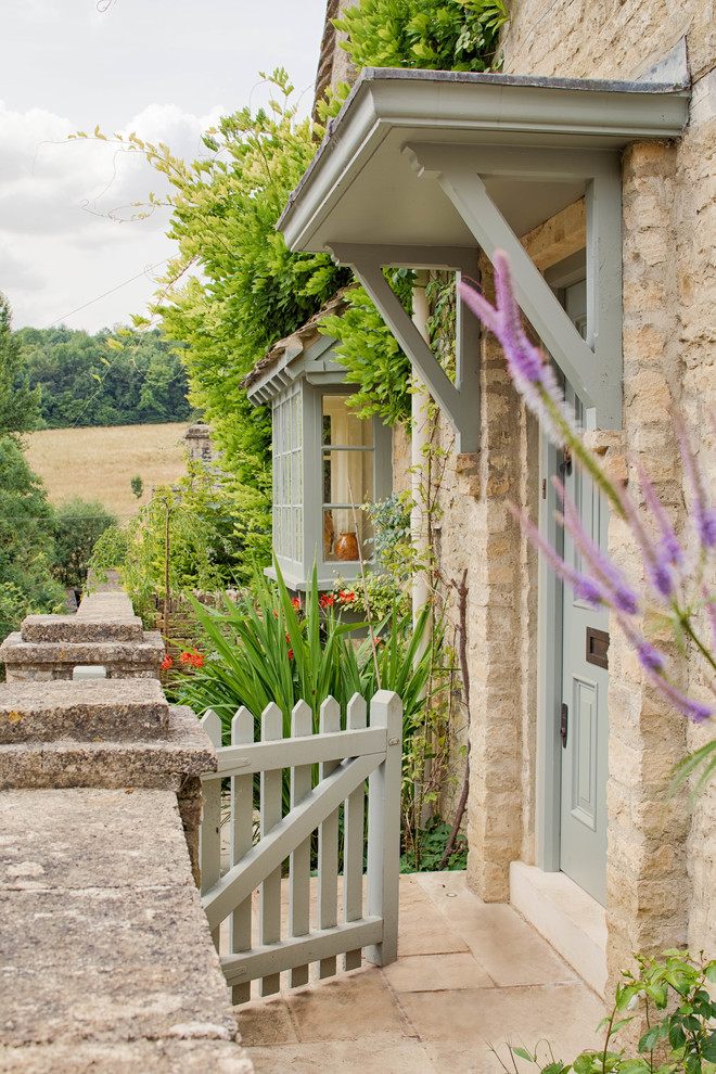 Inspiration for a country front door in Gloucestershire with beige walls, limestone floors, a single front door, a green front door and beige floor.