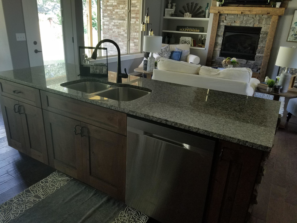 Inspiration for a mid-sized rustic single-wall dark wood floor and brown floor open concept kitchen remodel with an undermount sink, shaker cabinets, dark wood cabinets, granite countertops, beige backsplash, stone tile backsplash, stainless steel appliances and an island