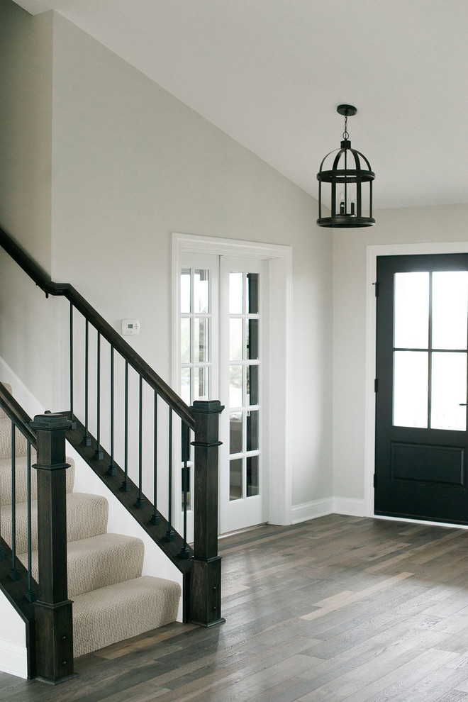 Inspiration for a mid-sized transitional foyer in Minneapolis with grey walls, medium hardwood floors, a single front door, a black front door and brown floor.