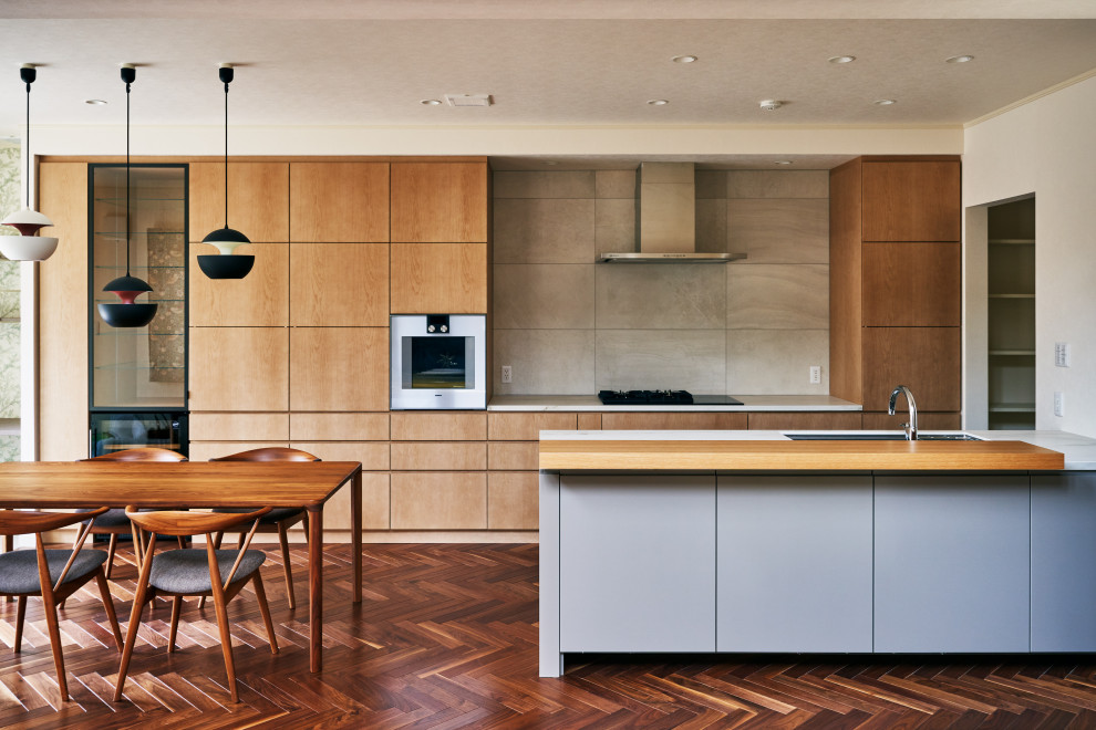 This is an example of a medium sized contemporary galley open plan kitchen in Tokyo with a submerged sink, beaded cabinets, medium wood cabinets, engineered stone countertops, grey splashback, ceramic splashback, stainless steel appliances, plywood flooring, an island, white worktops and a wallpapered ceiling.