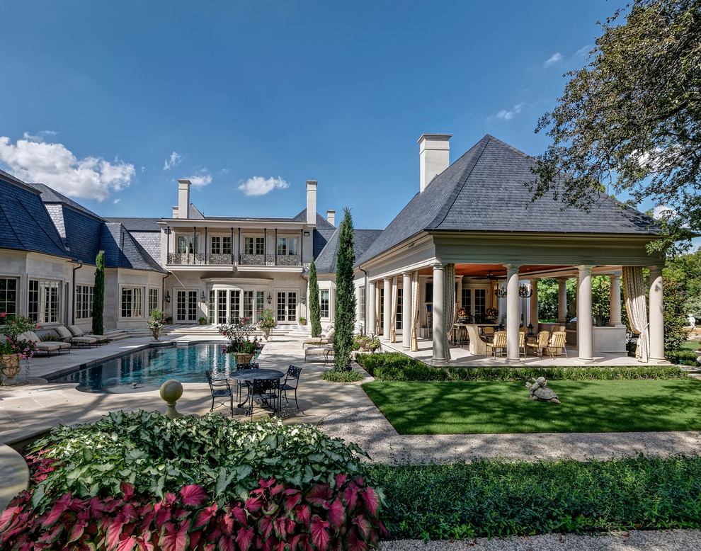 This is an example of a large traditional courtyard rectangular lap pool in Dallas with a pool house and natural stone pavers.