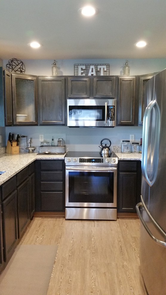 Photo of a small industrial u-shaped eat-in kitchen in Milwaukee with an undermount sink, shaker cabinets, black cabinets, granite benchtops, white splashback, subway tile splashback, stainless steel appliances, vinyl floors and a peninsula.