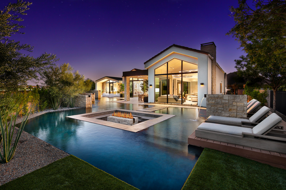 Photo of a contemporary backyard custom-shaped pool in Phoenix with a water feature and decking.