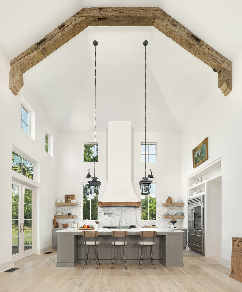 Inspiration for a traditional l-shaped kitchen in Charleston with shaker cabinets, grey cabinets, white splashback, stone slab splashback, stainless steel appliances, light hardwood floors, with island, beige floor and white benchtop.