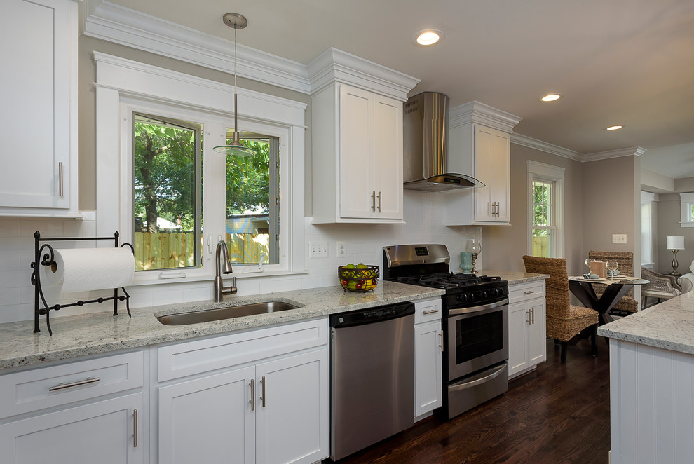 Large transitional l-shaped medium tone wood floor and brown floor eat-in kitchen photo in Baltimore with an undermount sink, shaker cabinets, white cabinets, granite countertops, white backsplash, ceramic backsplash, stainless steel appliances and an island