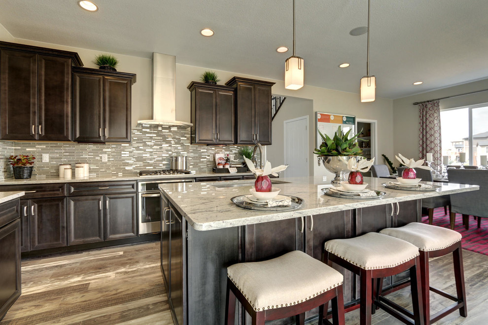 Mid-sized transitional l-shaped porcelain tile open concept kitchen photo in Denver with an undermount sink, recessed-panel cabinets, dark wood cabinets, granite countertops, white backsplash, mosaic tile backsplash, stainless steel appliances and an island