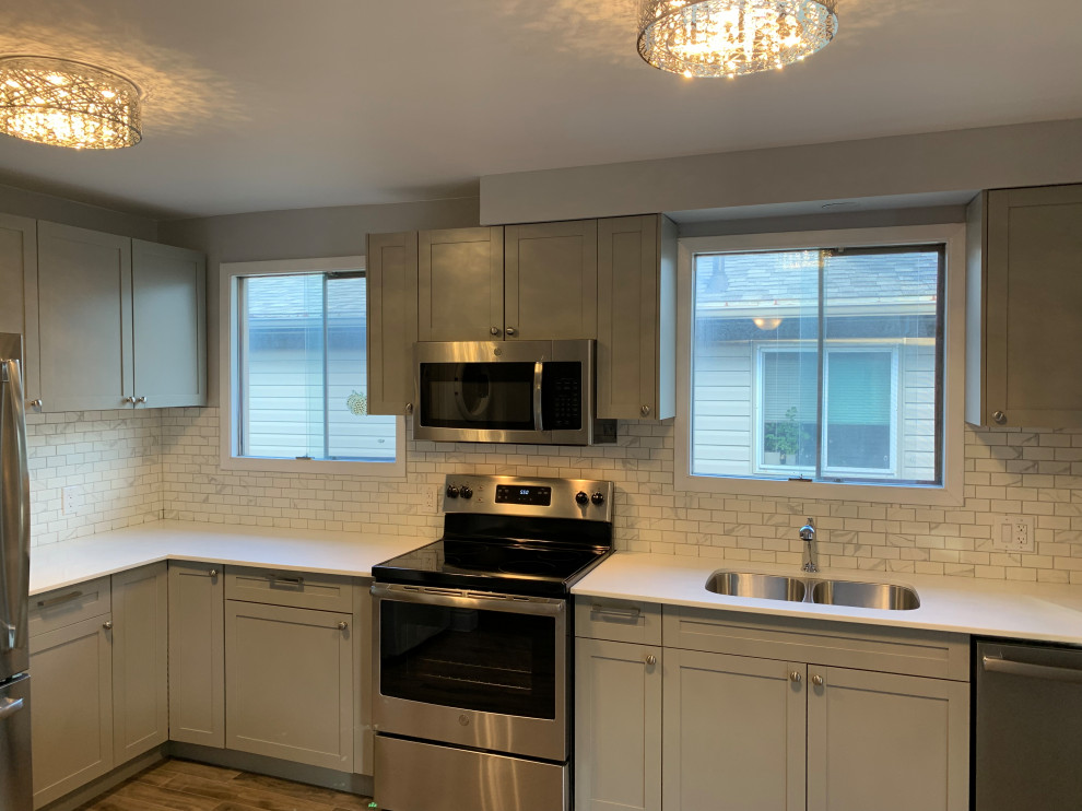 Kitchen - large transitional l-shaped medium tone wood floor kitchen idea with an undermount sink, shaker cabinets, gray cabinets, quartz countertops, white backsplash, marble backsplash, stainless steel appliances, an island and white countertops