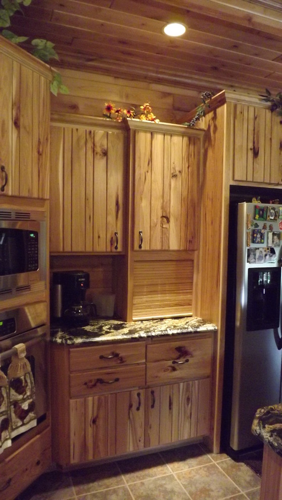 Example of a mountain style u-shaped porcelain tile and brown floor enclosed kitchen design with an undermount sink, stainless steel appliances and an island