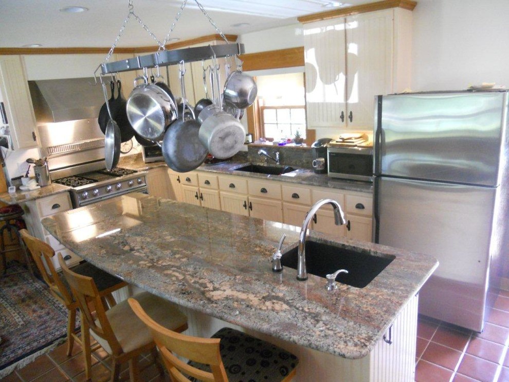 Eat-in kitchen - large farmhouse l-shaped terra-cotta tile eat-in kitchen idea in Portland Maine with an undermount sink, beaded inset cabinets, black cabinets, granite countertops, black backsplash, stainless steel appliances and an island