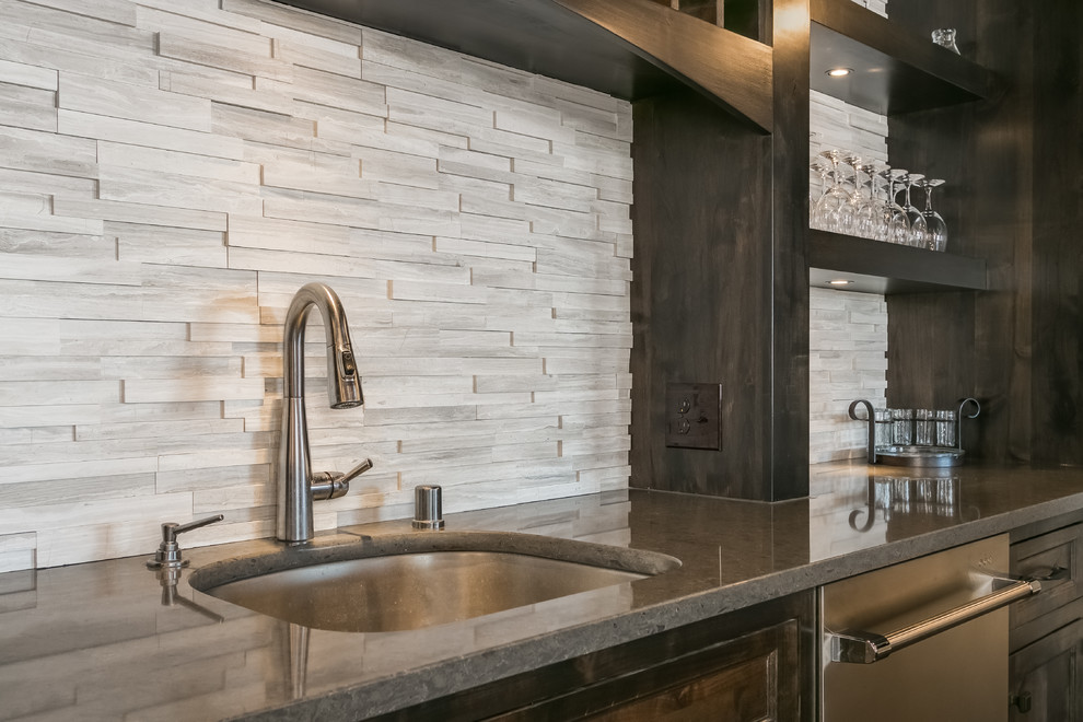 Inspiration for a large arts and crafts single-wall seated home bar in Minneapolis with an undermount sink, shaker cabinets, distressed cabinets, granite benchtops, white splashback, matchstick tile splashback, dark hardwood floors, brown floor and white benchtop.