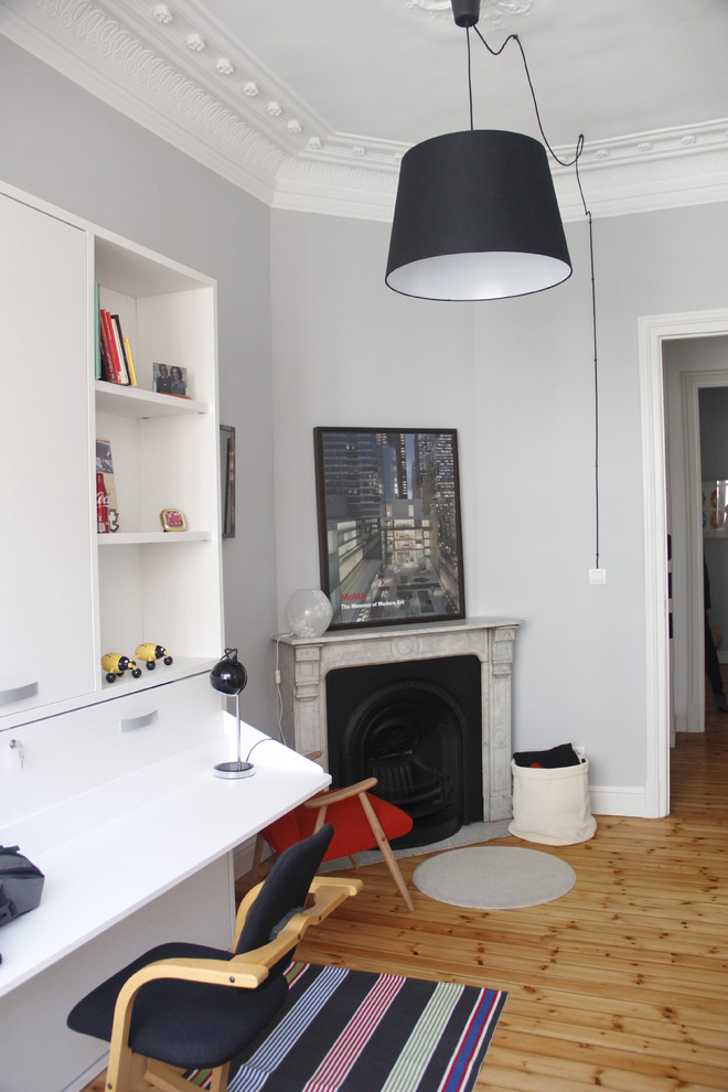 Modelo de dormitorio principal actual grande con paredes grises, chimenea de esquina, suelo de madera clara y marco de chimenea de piedra