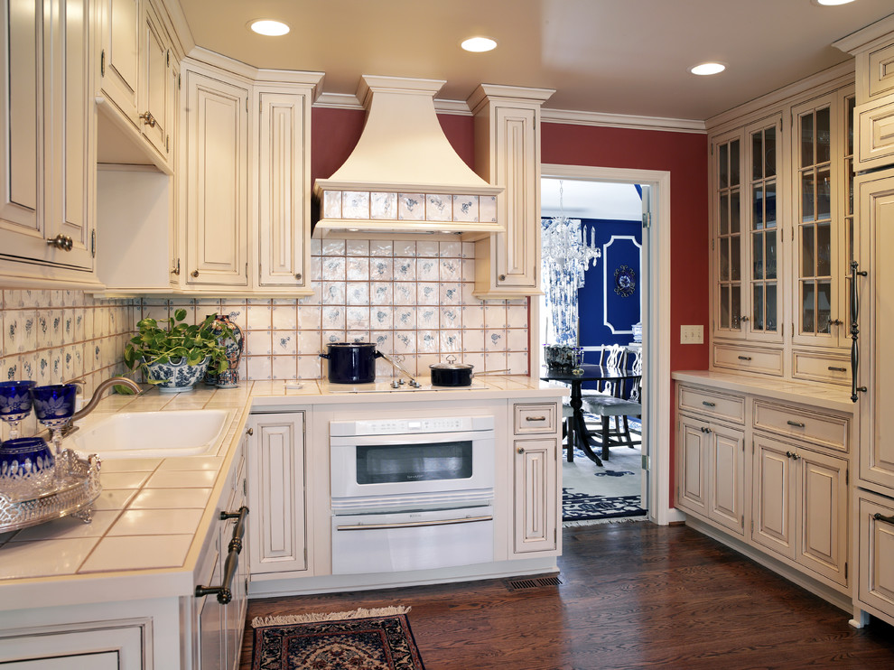 This is an example of a traditional separate kitchen in Kansas City with raised-panel cabinets, beige cabinets, tile benchtops and white appliances.