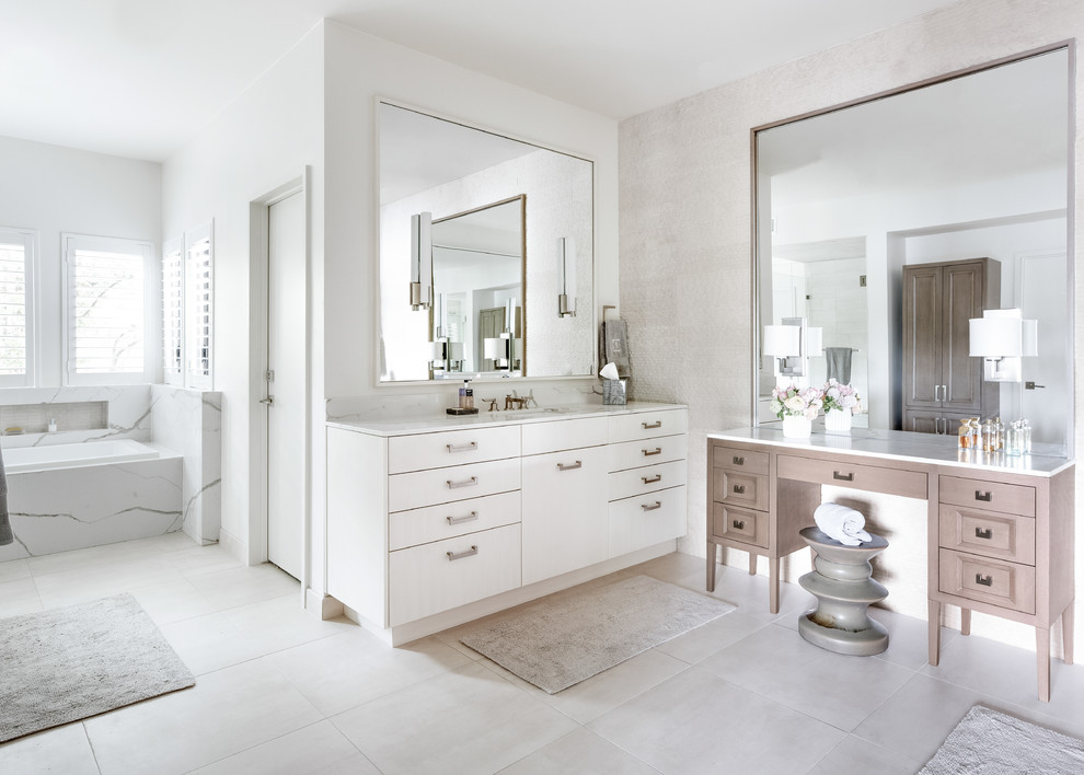 Photo of a transitional master bathroom in Dallas with a drop-in tub, a one-piece toilet, white tile, limestone, white walls, porcelain floors, beige floor, white benchtops, flat-panel cabinets, white cabinets and an undermount sink.