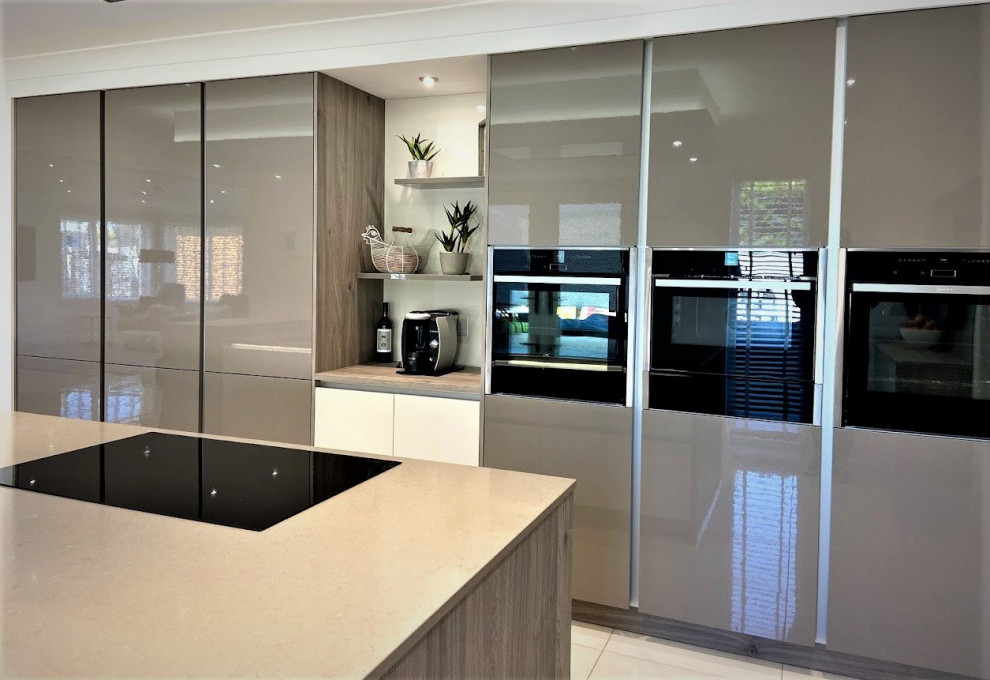Example of a minimalist single-wall white floor eat-in kitchen design in Other with a double-bowl sink, flat-panel cabinets, gray cabinets, quartzite countertops, black appliances, an island and brown countertops