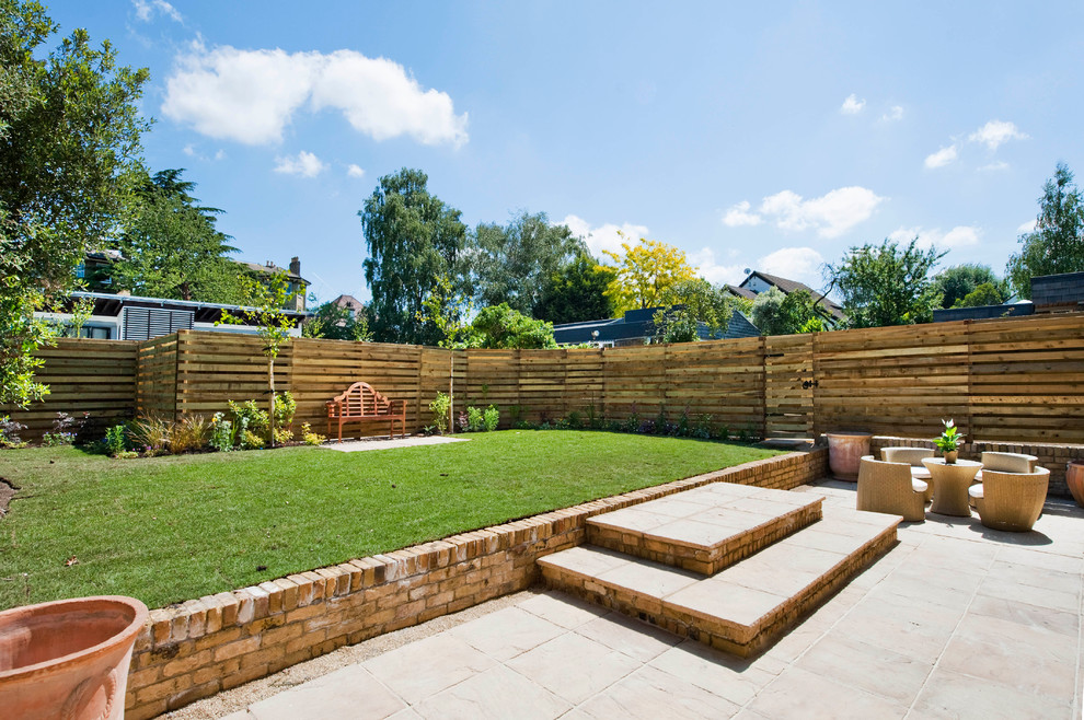 This is an example of a traditional backyard full sun garden in London.