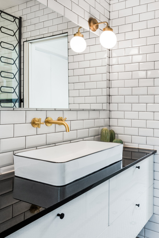 Design ideas for a mid-sized modern 3/4 bathroom in Chicago with flat-panel cabinets, white cabinets, a shower/bathtub combo, a one-piece toilet, black and white tile, white walls, a vessel sink, white floor, a hinged shower door, black benchtops, a single vanity and a floating vanity.