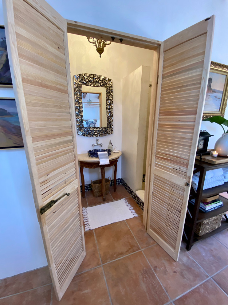 Пример оригинального дизайна: маленькая ванная комната в белых тонах с отделкой деревом в средиземноморском стиле с искусственно-состаренными фасадами, открытым душем, раздельным унитазом, белой плиткой, цементной плиткой, белыми стенами, полом из терракотовой плитки, душевой кабиной, настольной раковиной, мраморной столешницей, оранжевым полом, открытым душем, бежевой столешницей, тумбой под одну раковину, напольной тумбой и балками на потолке для на участке и в саду