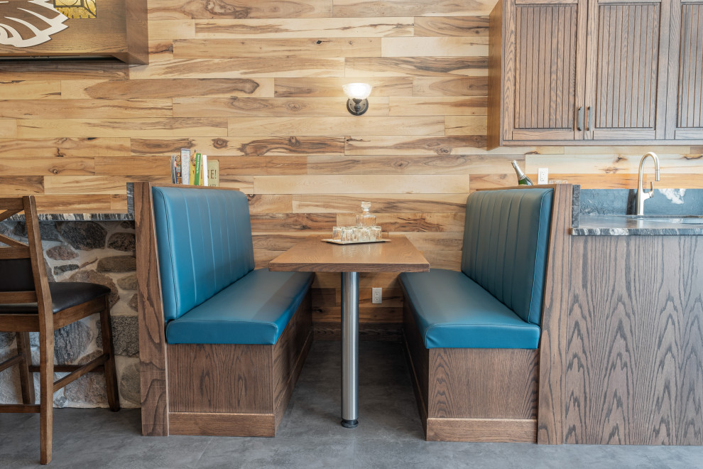Example of a large mountain style walk-out vinyl floor, gray floor, exposed beam and wood wall basement design with a bar, multicolored walls, a standard fireplace and a stone fireplace