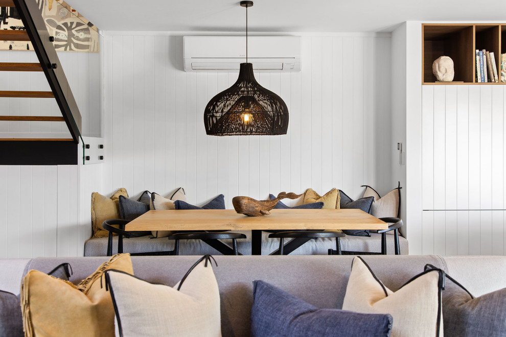 Aménagement d'une petite salle à manger bord de mer avec une banquette d'angle, un mur blanc, parquet clair, un sol marron, un plafond voûté et du lambris de bois.