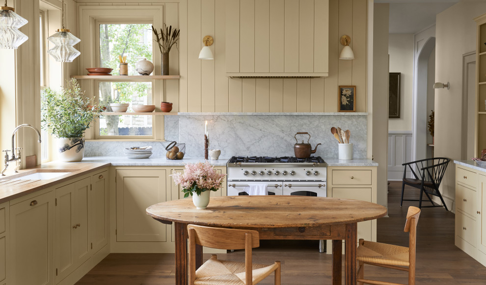 Design ideas for a mid-sized traditional eat-in kitchen in Columbus with shaker cabinets, yellow cabinets, marble benchtops, grey splashback, marble splashback, white appliances, medium hardwood floors, no island, brown floor and grey benchtop.