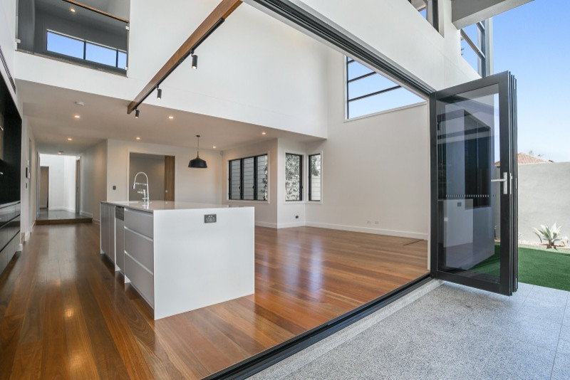 Inspiration for a mid-sized contemporary galley kitchen pantry in Brisbane with a drop-in sink, medium wood cabinets, quartz benchtops, white splashback, marble splashback, black appliances, medium hardwood floors, with island, brown floor and white benchtop.