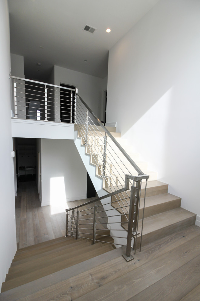 Foto de escalera suspendida minimalista de tamaño medio con escalones de madera, contrahuellas de madera, barandilla de metal y machihembrado