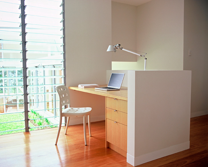 This is an example of a contemporary study room in Sydney with grey walls, medium hardwood floors and a built-in desk.