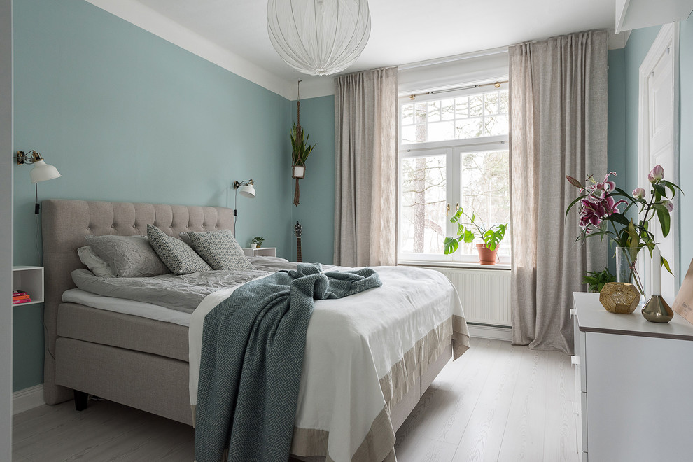 Scandinavian bedroom in Stockholm with blue walls, laminate floors and beige floor.