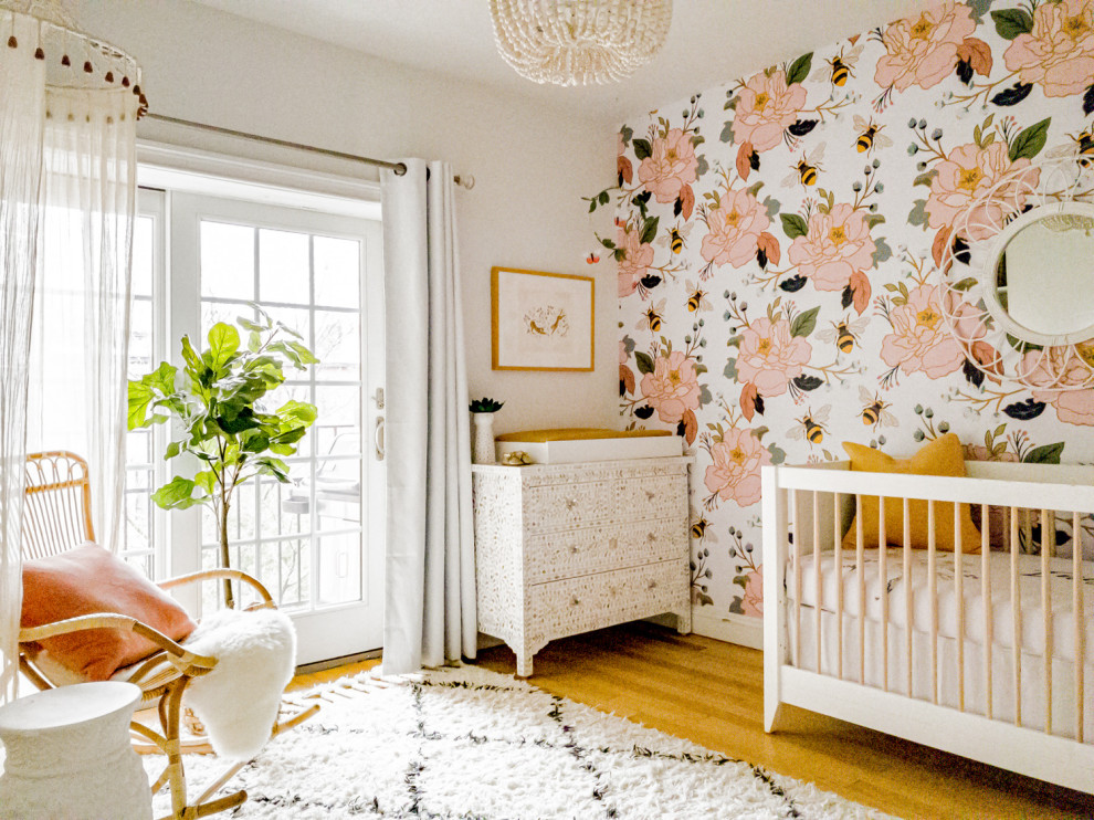 Design ideas for a mid-sized eclectic nursery for girls in New York with multi-coloured walls, light hardwood floors and brown floor.