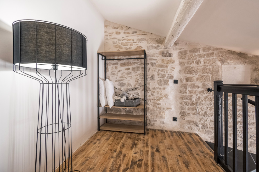 Inspiration for a small modern loft-style bedroom in Other with white walls, brown floor and wood.