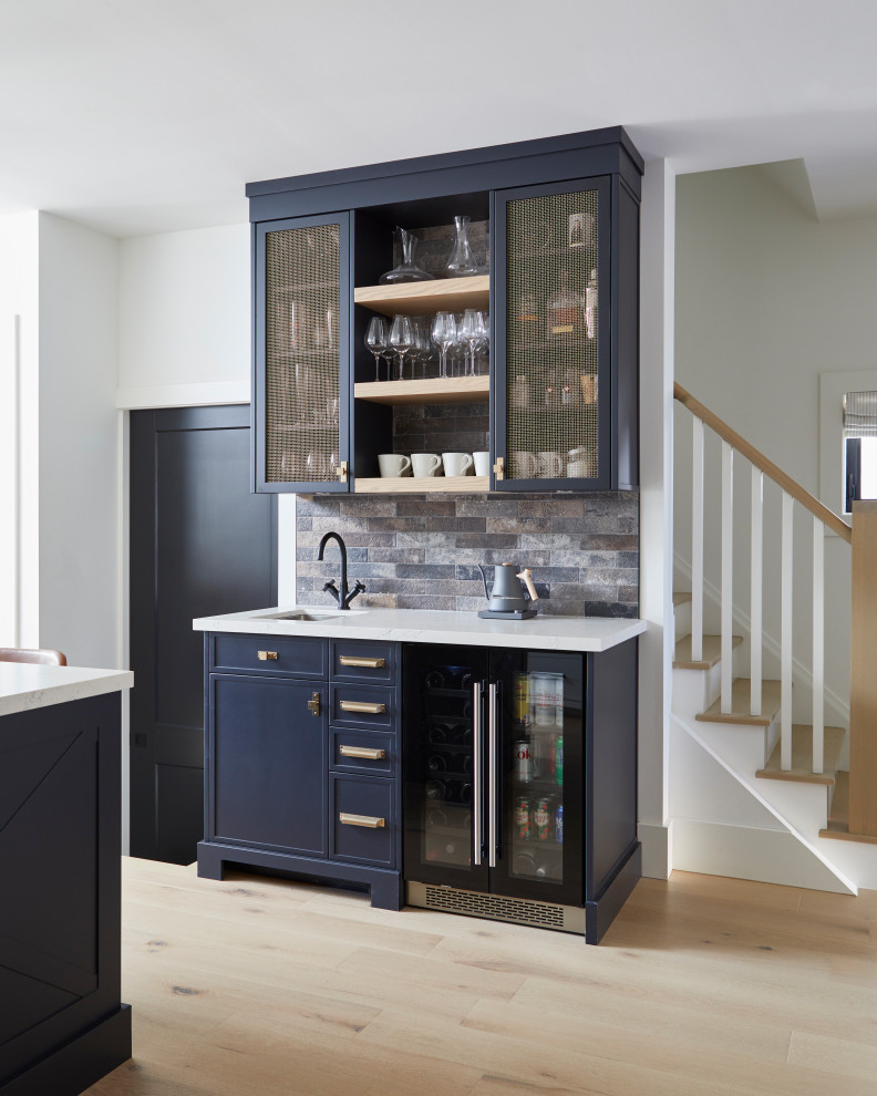 Design ideas for a small transitional single-wall wet bar in Toronto with an undermount sink, recessed-panel cabinets, blue cabinets, quartz benchtops, multi-coloured splashback, stone tile splashback, light hardwood floors, beige floor and white benchtop.