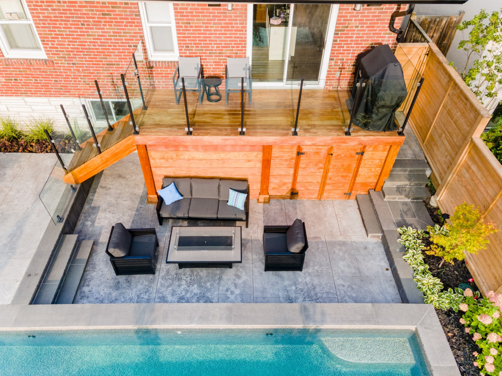 Modelo de piscina tradicional renovada de tamaño medio rectangular en patio trasero con paisajismo de piscina y suelo de hormigón estampado
