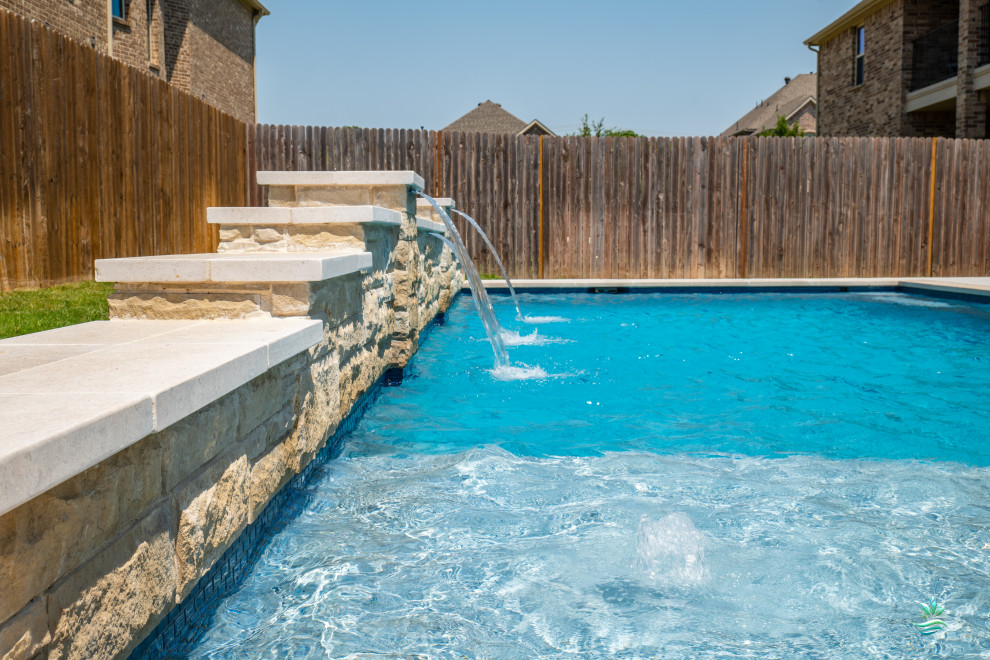 Diseño de piscina alargada de estilo americano de tamaño medio rectangular en patio trasero con paisajismo de piscina y losas de hormigón
