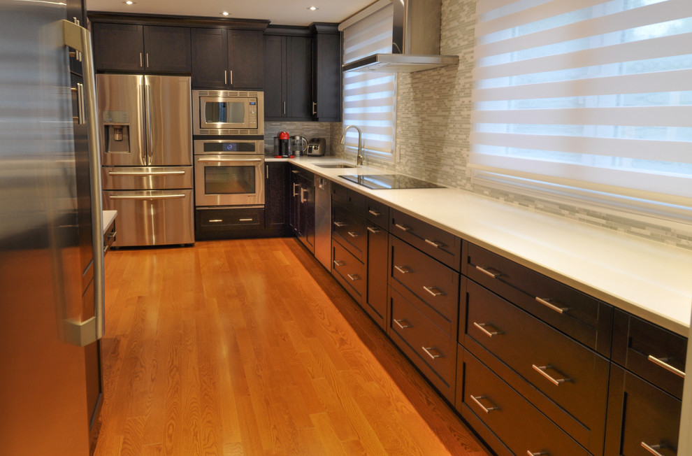 Example of a large transitional galley light wood floor and brown floor enclosed kitchen design in Toronto with a single-bowl sink, shaker cabinets, dark wood cabinets, quartzite countertops, beige backsplash, stone tile backsplash, stainless steel appliances and an island