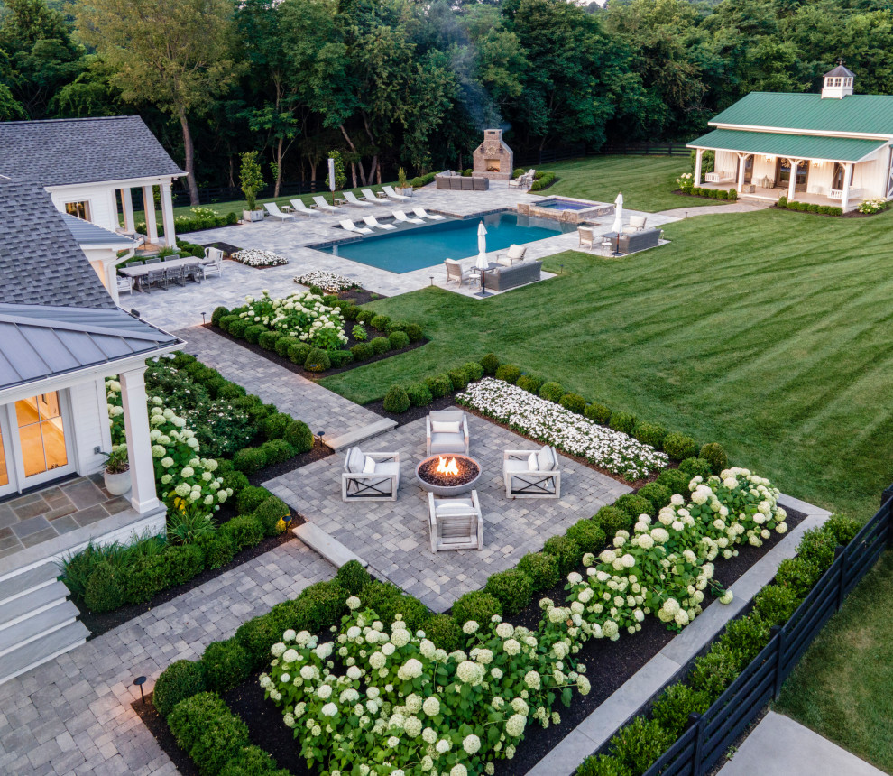 Design ideas for a large country backyard custom-shaped pool in Nashville with natural stone pavers.