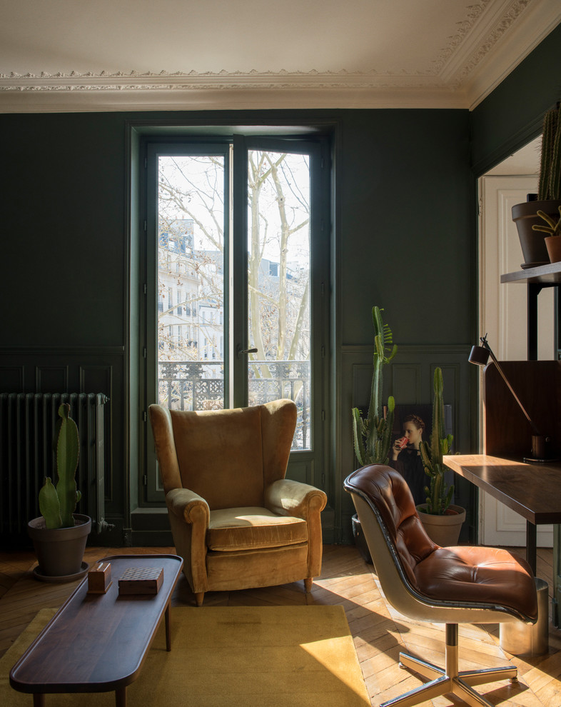 Eclectic study room in Paris with green walls, medium hardwood floors, a freestanding desk and beige floor.