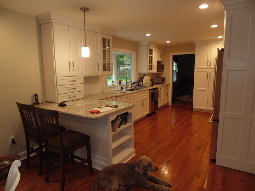 Example of a mid-sized transitional medium tone wood floor and brown floor eat-in kitchen design with an undermount sink, recessed-panel cabinets, white cabinets, granite countertops, white backsplash, subway tile backsplash, stainless steel appliances, no island and white countertops