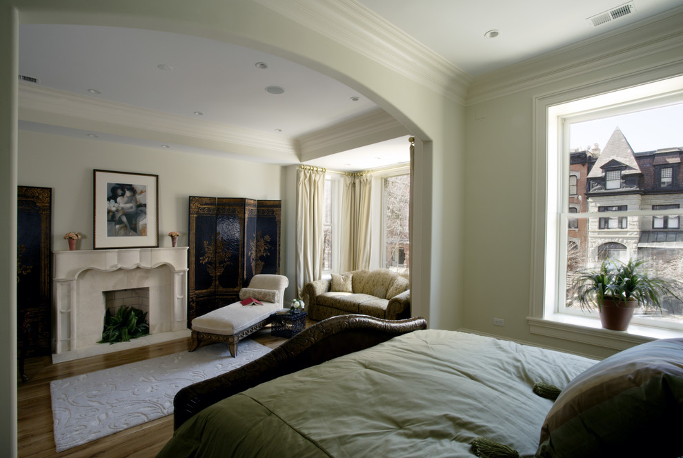 Large traditional master bedroom in Chicago with beige walls, light hardwood floors, a standard fireplace and a stone fireplace surround.