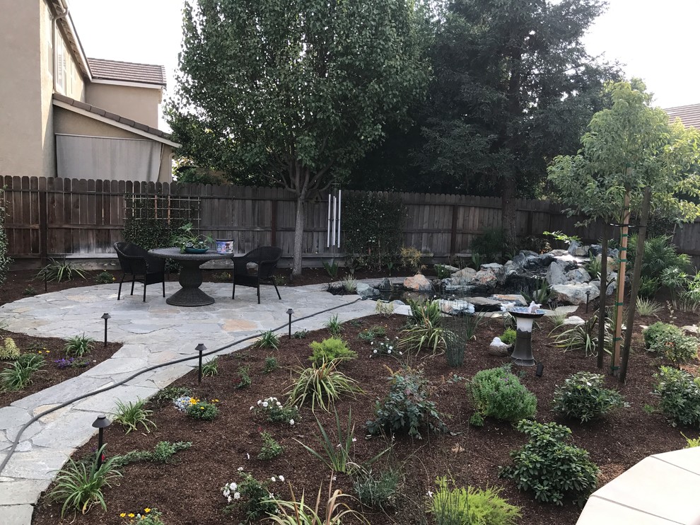 Example of a mid-sized transitional backyard stone patio design with no cover