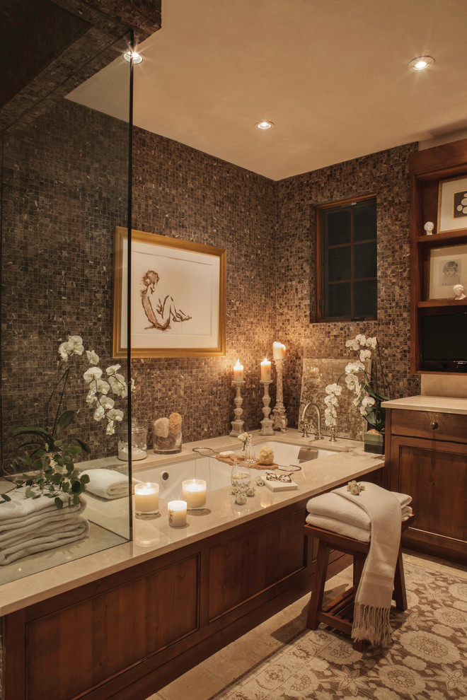 This is an example of a mid-sized eclectic master bathroom in Chicago with furniture-like cabinets, medium wood cabinets, multi-coloured tile, pebble tile, beige walls, ceramic floors, marble benchtops, beige floor and an undermount tub.
