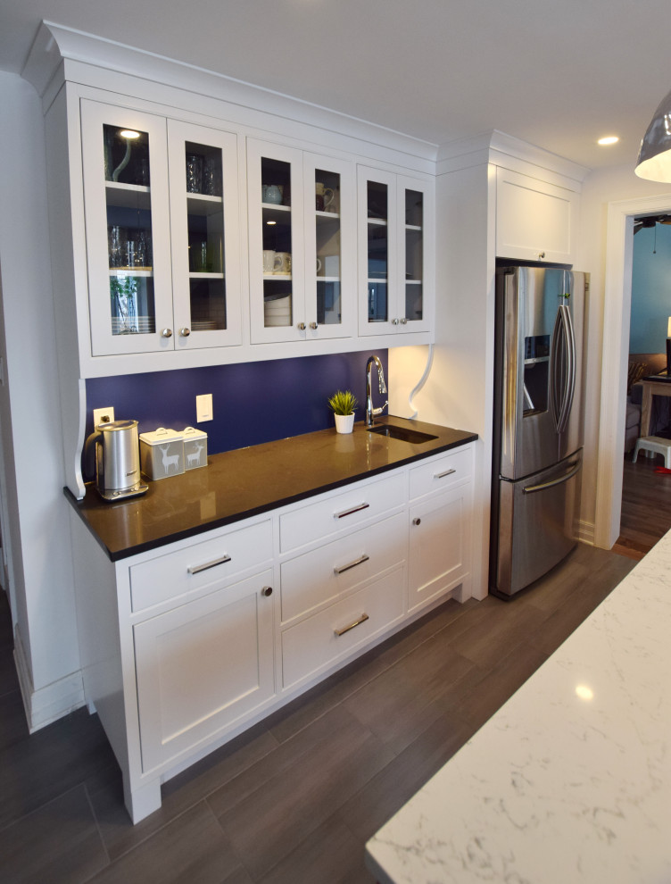 Small eclectic galley light wood floor and beige floor enclosed kitchen photo in Ottawa with an undermount sink, shaker cabinets, white cabinets, quartz countertops, white backsplash, subway tile backsplash, stainless steel appliances, an island and white countertops